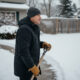 Homme en parka et bonnet shovellant la neige